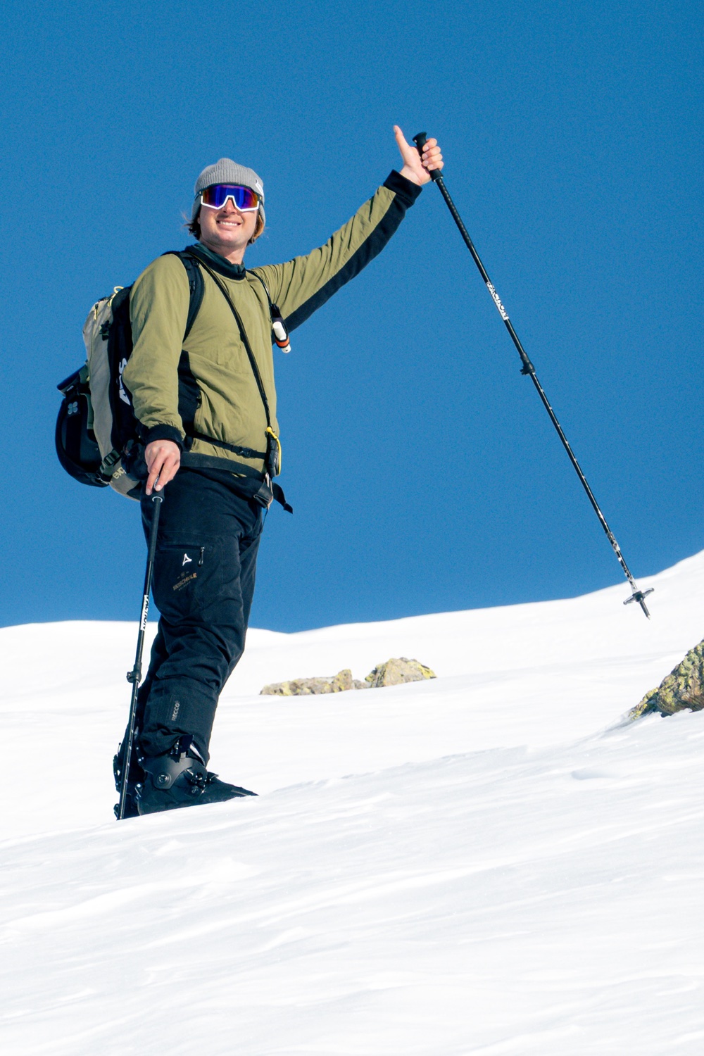 Max mit Skiausrüstung und erhobenem Stock im Schnee